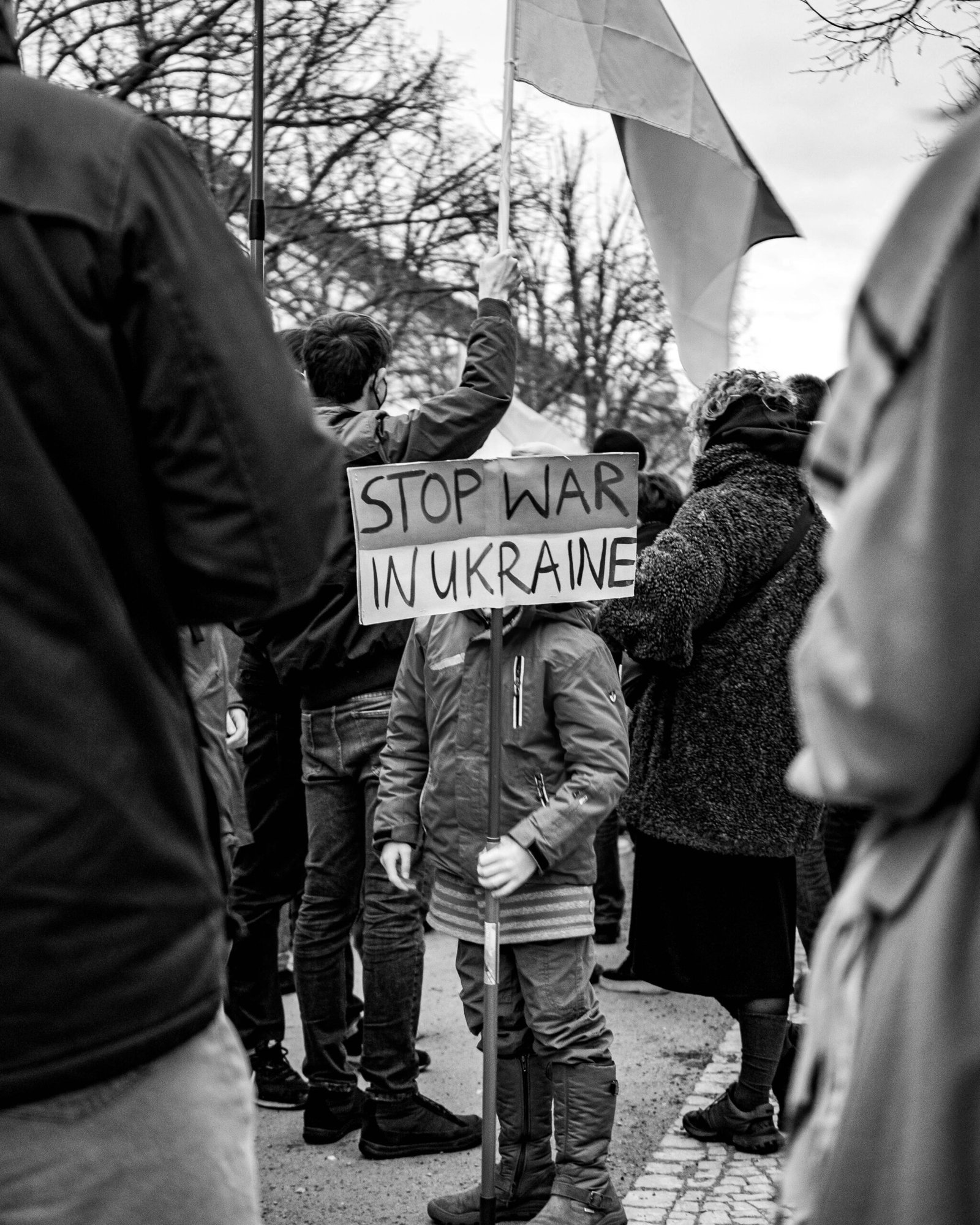 Home Grayscale protest in Berlin with child holding 'Stop War in Ukraine' sign.