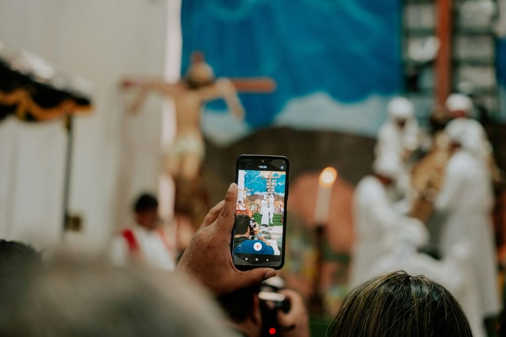 A person records a spiritual ceremony with a smartphone, focusing on religious symbolism and community.