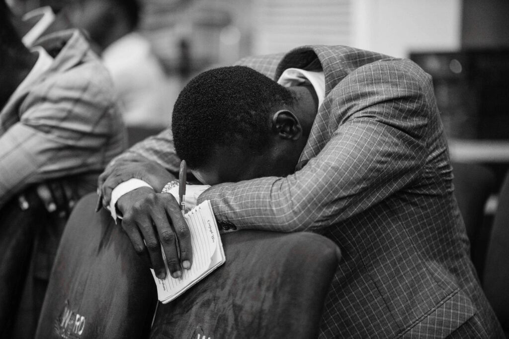 Black and white image of a man praying with devotion in a Nigerian church.