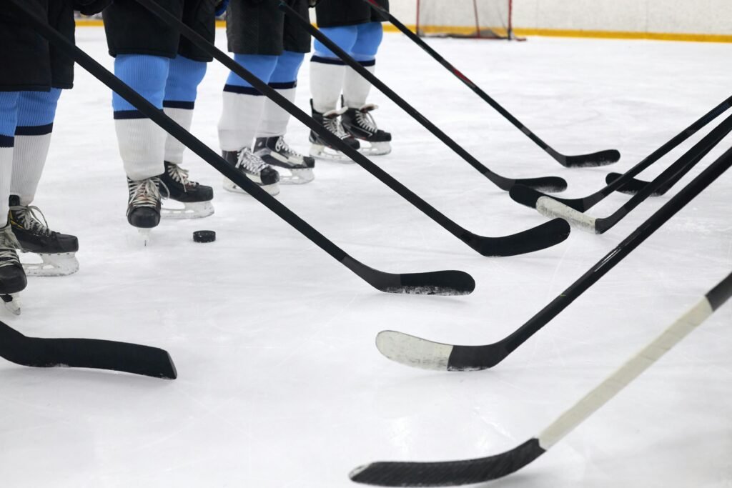 Close-up of hockey players on ice with sticks ready for a faceoff.
